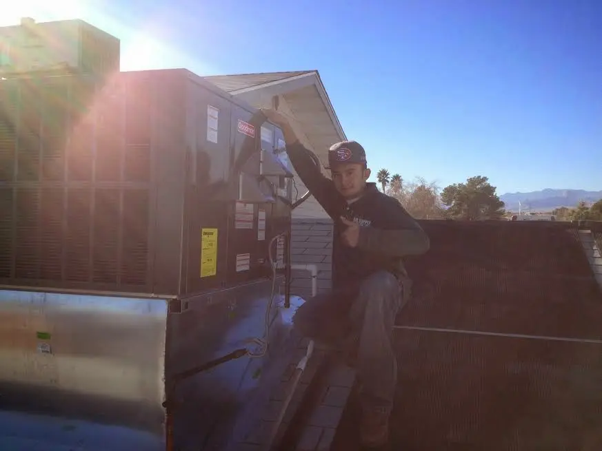 HVAC technician performing AC Tune-Up on a rooftop unit in Bountiful